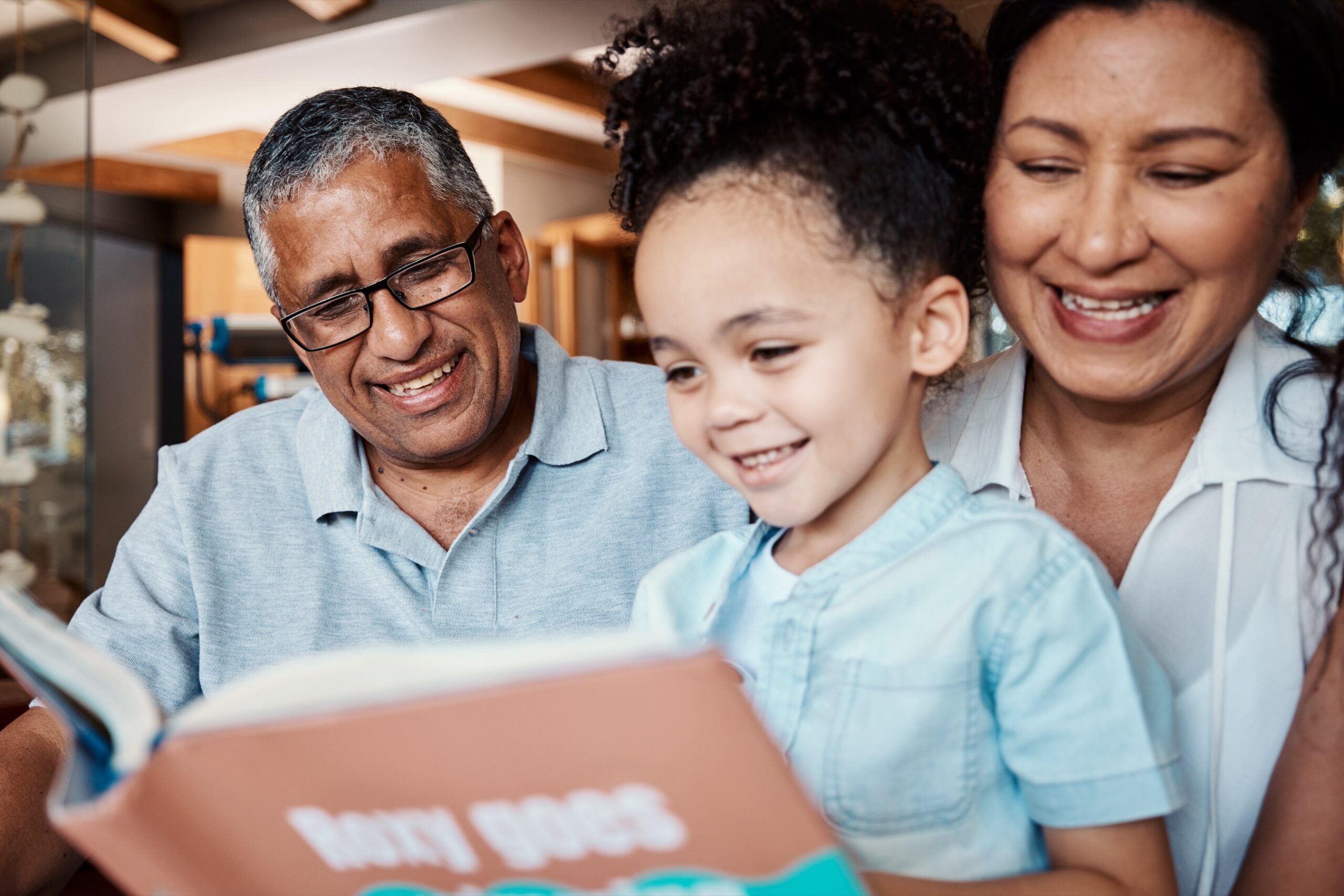 Grandparent reading a book with grandchildren on the sofa
