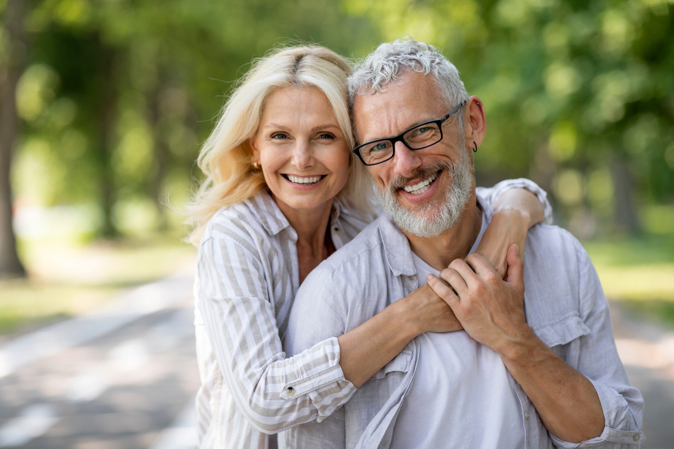 Cheerful older couple hugging and smiling outdoors