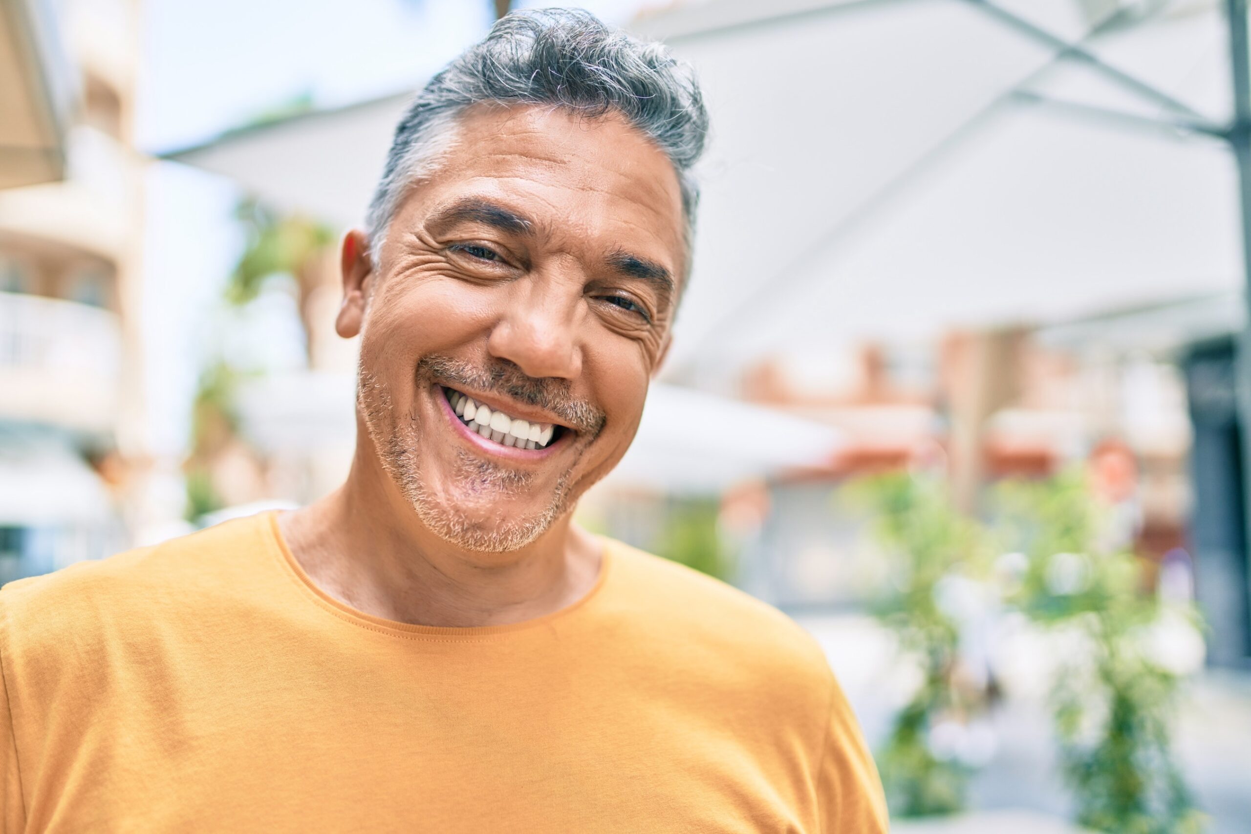 Grey-haired man smiling while walking through the city