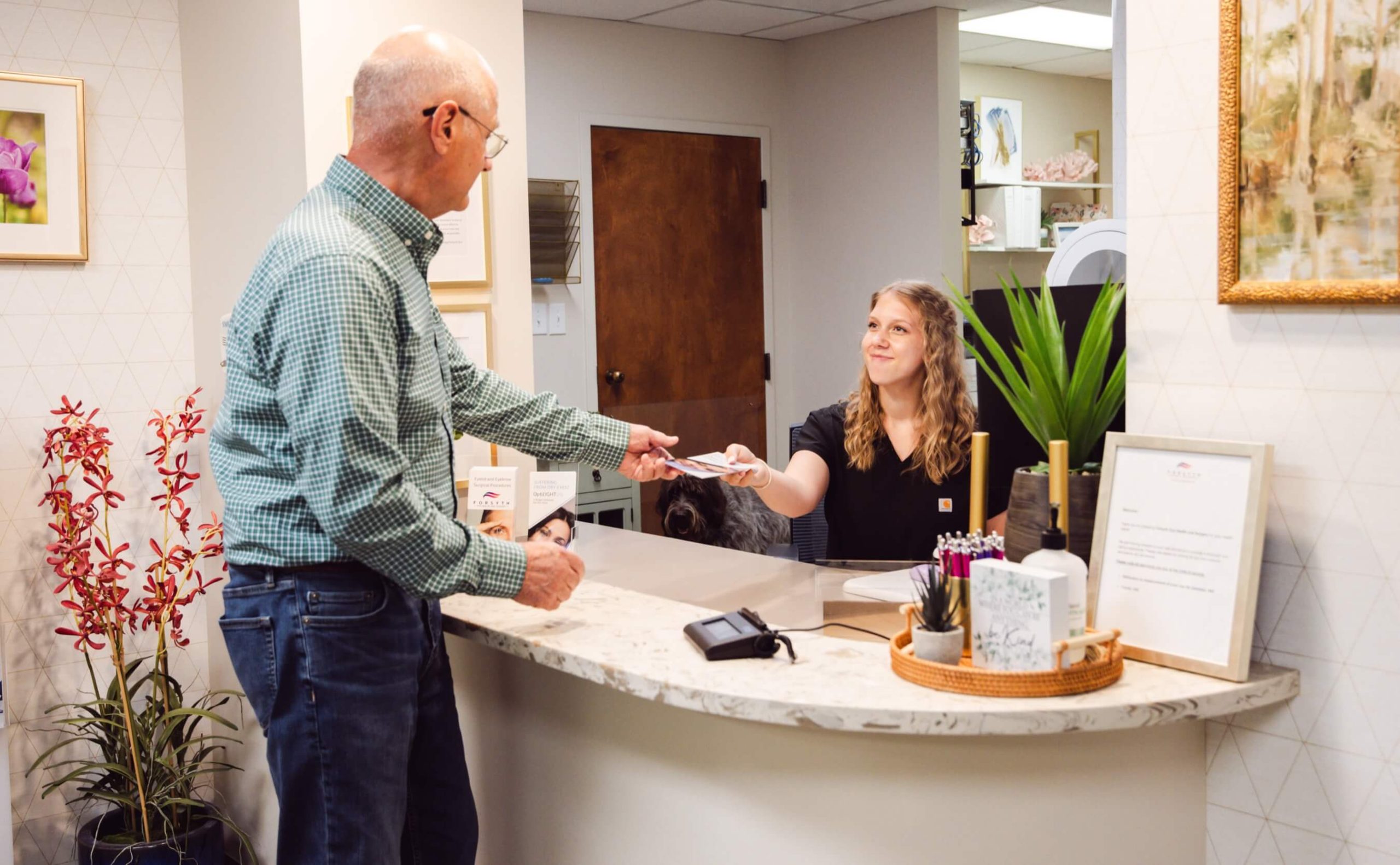 Patient handing a payment card to a staff member at the Forsyth Eye Health front desk