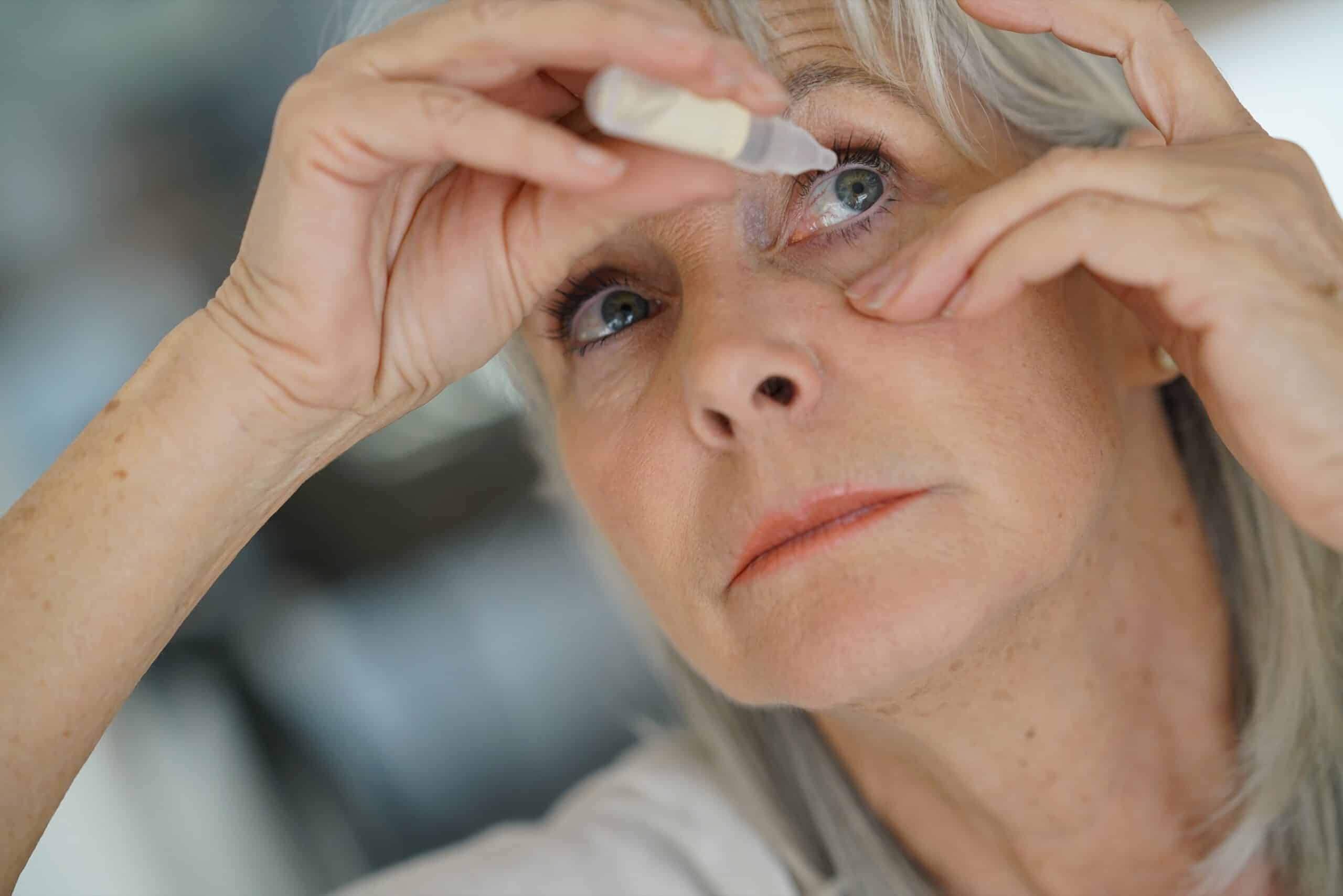 Senior woman putting in an eye drop