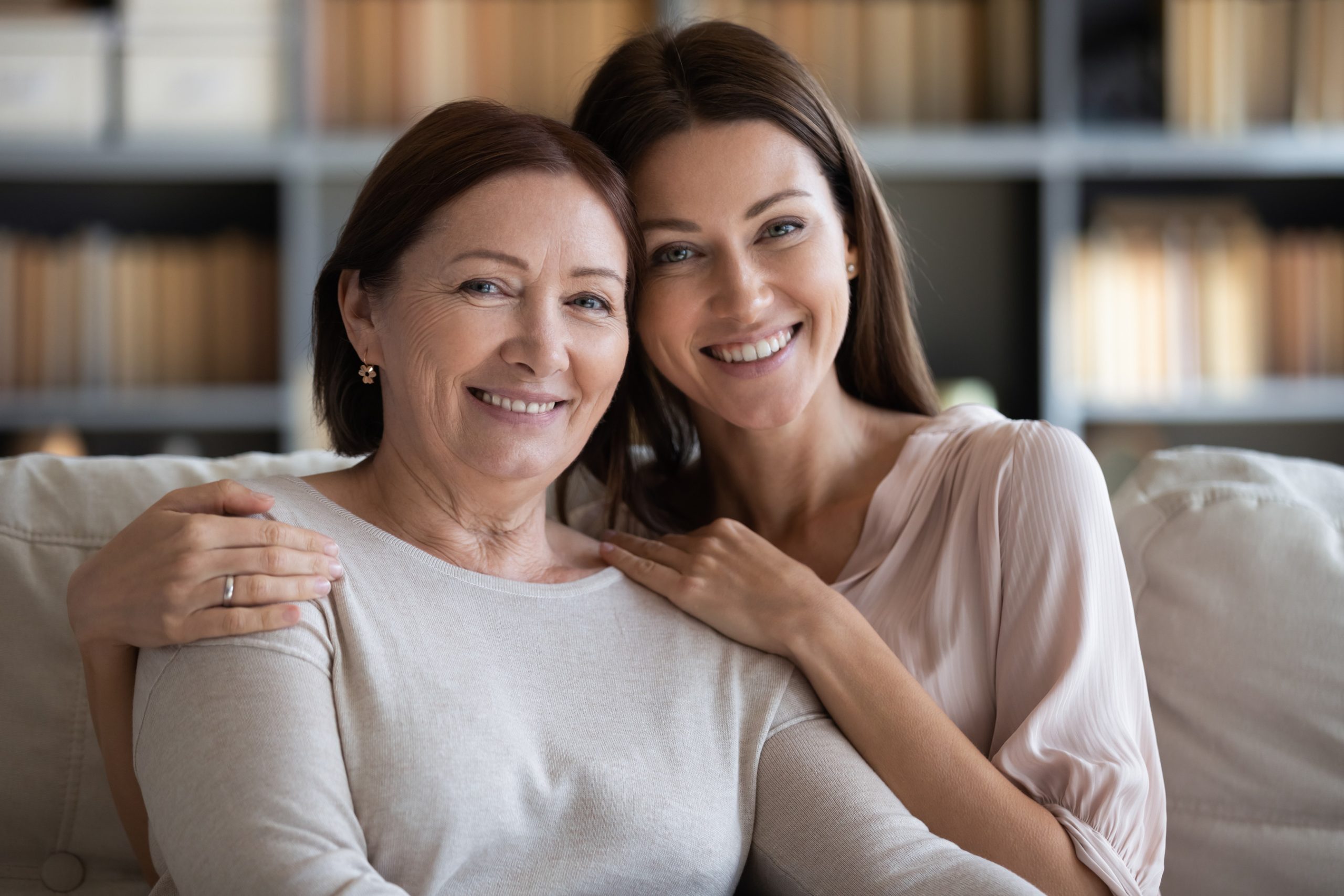 Smiling mother and adult daughter sitting together at home